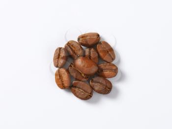 Handful of roasted coffee beans on white background