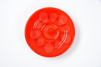 empty red saucer on off-white background