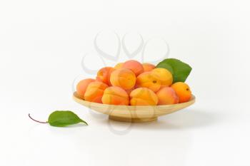 Heap of fresh ripe apricots on bamboo plate