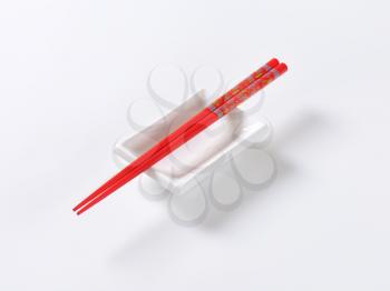 A pair of red chopsticks on empty soy sauce dish