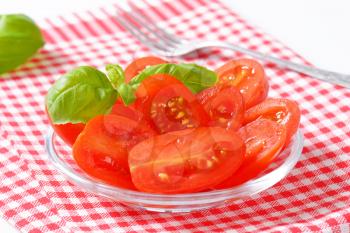 Halved fresh Roma tomatoes on glass plate