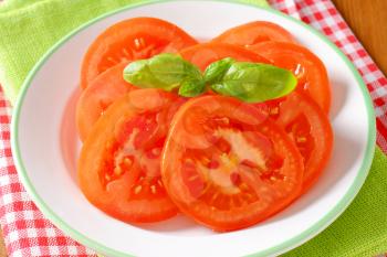 sliced tomato with basil on white plate