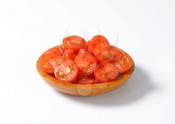 Halved cherry tomatoes in wooden bowl