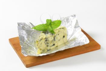 Wedge of French blue cheese on foil
