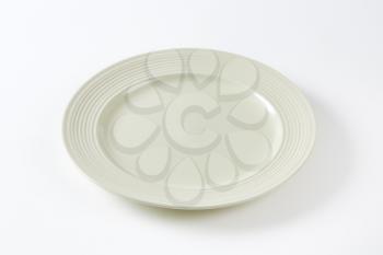 Bone white dinner plate with embossed rings on the rim