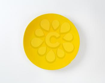 Rimless round plate with yellow glaze