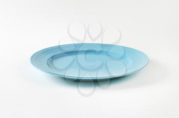 Blue glazed dinner plate with embossed concentric rings on the edge