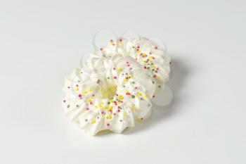 Two wreath-shaped meringue cookies topped with sprinkles