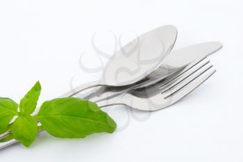 knife, fork and spoon and fresh basil leaves