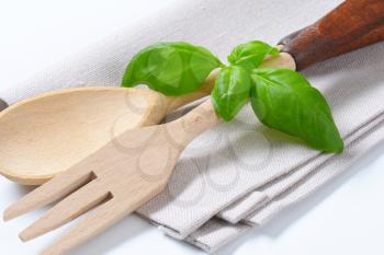wooden fork and spoon with fresh basil on napkin