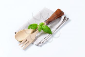 wooden fork and spoon with fresh basil on napkin
