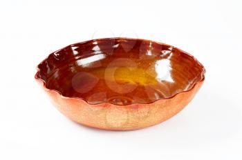 scalloped edge brown pottery bowl on white background