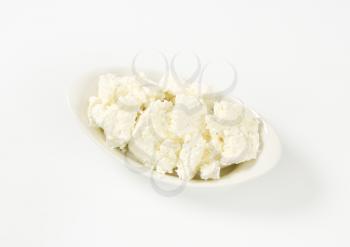pieces of fresh curd cheese in white bowl