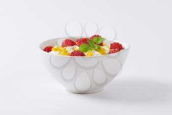 healthy breakfast - bowl of yoghurt with raspberries  and cornflakes
