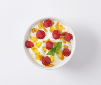 healthy breakfast - bowl of yoghurt with raspberries  and cornflakes