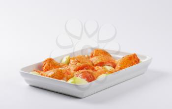 marinated chicken legs in white ceramic baking dish