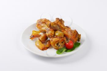 freshly roasted chicken legs and vegetables on white plate