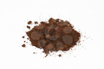 heap of freshly ground coffee on white background