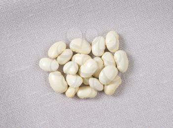 handful of raw white beans on tablecloth