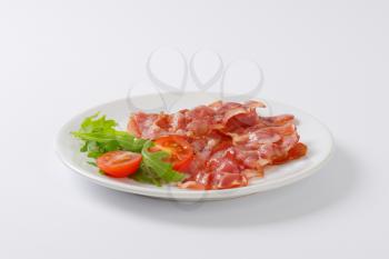 Cooked rashers of streaky bacon on plate