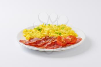 plate of scrambled eggs and slices of cooked rashers of bacon