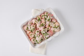 raw chicken wings with chopped parsley in white ceramic baking dish