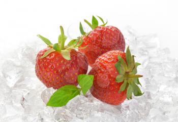 close up of three fresh strawberries on ice