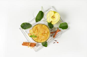 bowl of apple sauce, cinnamon sticks and cloves on wooden cutting board