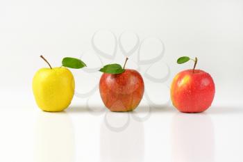 three washed apples in a row on white background