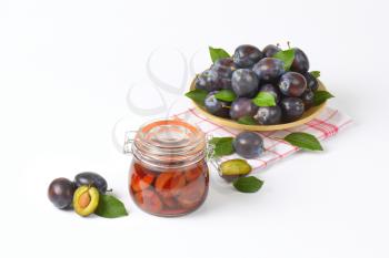 plate of fresh plums and jar of preserved plums