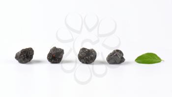 dried plums and plum leaf on white background