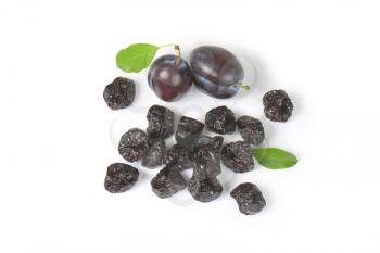 fresh and dried plums on white background