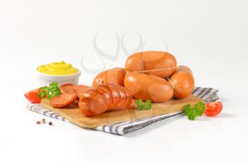 raw and roasted sausages on cutting board and bowl of mustard