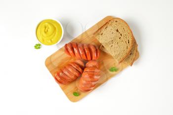 roasted sausages, bowl of mustard and sliced bread