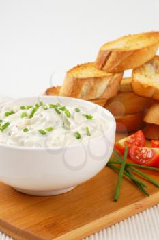 slices of toasted baguette and bowl of chives cheese spread