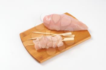 raw chicken breast fillet and wooden skewers on cutting board