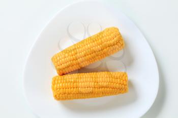 two boiled corn cobs on white plate