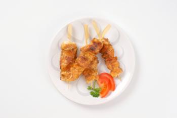 four spicy chicken skewers on plate