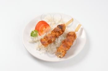 rice and grilled chicken skewers on white plate