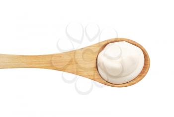 Fresh white cream on a  small deep wooden spoon