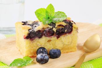 a piece of homemade blueberry cake on a wooden cutting board