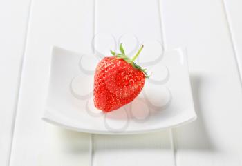 Ripe red strawberry on square white plate