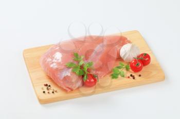 Raw turkey breast with tomatoes and garlic on cutting board