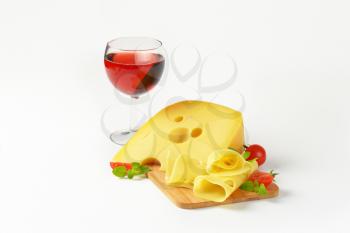 yellow medium-hard cheese with eyes and glass of red wine