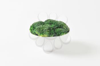 Raw broccoli florets in white bowl 