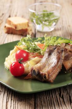 Roast pork ribs and mashed potato garnished with salad greens
