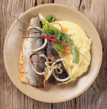 Pan fried trout with mashed potatoes on wooden background