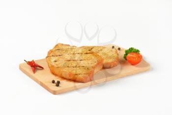 Two grilled honey glazed pork chops on cutting board