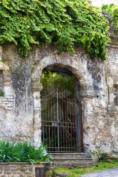 Gated arched entrance in a weathered wall in the Tuscan village of Bagni San Filippo, Italy