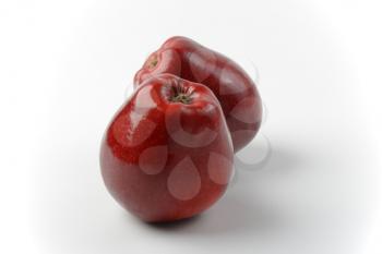 two glossy red apples on off-white background